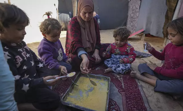 Yasmin Eid and her four daughters eat lentils at their tent in a refugee camp in Deir al-Balah, Gaza Strip, Tuesday Nov. 19, 2024. (AP Photo/Abdel Kareem Hana)