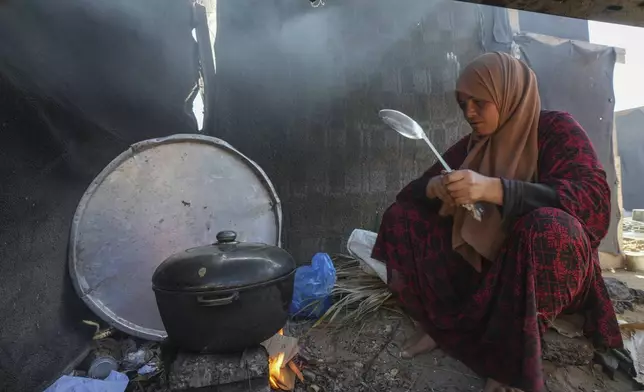 Yasmin Eid cooks at her family's tent in a refugee camp in Deir al-Balah, Gaza Strip, Tuesday, Nov. 19, 2024. (AP Photo/Abdel Kareem Hana)