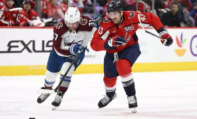 Washington Capitals right wing Tom Wilson (43) and Colorado Avalanche center Casey Mittelstadt (37) chase the puck during the first period of an NHL hockey game, Thursday, Nov. 21, 2024, in Washington. (AP Photo/Nick Wass)