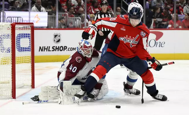 Washington Capitals center Lars Eller (20) battles on the puck against Colorado Avalanche goalie Alexandar Georgiev (40) during the first period of an NHL hockey game, Thursday, Nov. 21, 2024, in Washington. (AP Photo/Nick Wass)