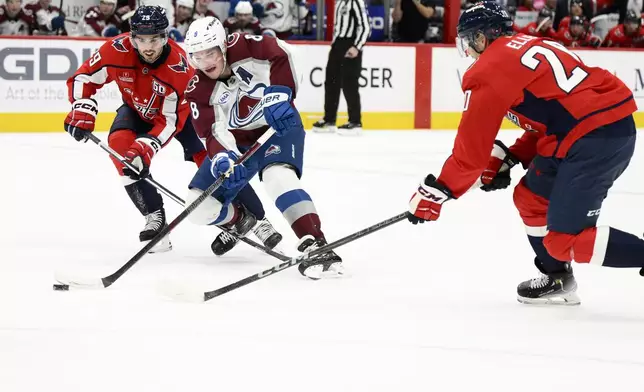 Colorado Avalanche defenseman Cale Makar (8) skates with the puck against Washington Capitals center Lars Eller (20) and center Hendrix Lapierre (29) during the second period of an NHL hockey game, Thursday, Nov. 21, 2024, in Washington. (AP Photo/Nick Wass)