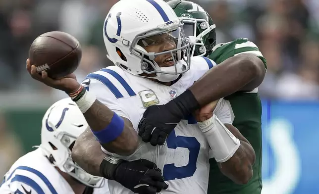 Indianapolis Colts quarterback Anthony Richardson (5) throws under pressure from New York Jets defensive end Micheal Clemons (72) during the third quarter of an NFL football game, Sunday, Nov. 17, 2024, in East Rutherford, N.J. (AP Photo/Adam Hunger)