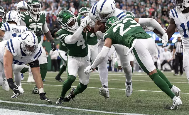 Indianapolis Colts quarterback Anthony Richardson (5) breaks through tackles by New York Jets cornerback Isaiah Oliver (23) and cornerback D.J. Reed (4) to score a touchdown during the fourth quarter of an NFL football game, Sunday, Nov. 17, 2024, in East Rutherford, N.J. (AP Photo/Adam Hunger)