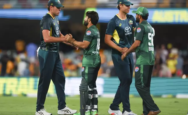 Pakistan's Mohammad Rizwan, congratulates Australia's Xavier Bartlett, left, and Pakistan's Babar Azam, right, congratulates Australia's Spencer Johnson following their T20 cricket international between Pakistan and Australia at the Gabba in Brisbane, Australia, Thursday, Nov. 14, 2024. (AP Photo/Tertius Pickard)