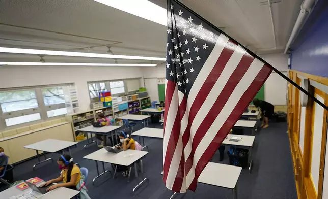 FILE - An American flag hangs in a classroom as students work on laptops in Newlon Elementary School, Aug. 25, 2020, in Denver. (AP Photo/David Zalubowski, File)