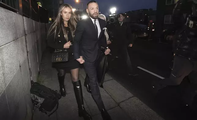 Mixed martial arts fighter Conor McGregor, right, and partner Dee Devlin outside the High Court in Dublin Friday, Nov. 22, 2024, where he is appearing for a personal injury case against him. (Brian Lawless/PA via AP)