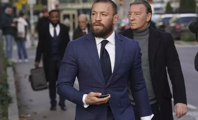 Mixed martial arts fighter Conor McGregor, front, and his father Tony, right, outside the High Court in Dublin, Ireland, Thursday, Nov. 21, 2024. (Brian Lawless/PA via AP)