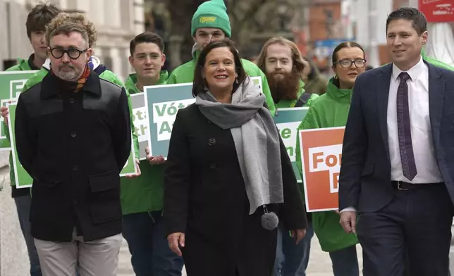 Sinn Fein leader Mary Lou McDonald, center, walks with candidates Eoin O Broin, left, Matt Carthy, right, and supporters arrive at Government Buildings, on the last day of campaigning on the eve of the General Election, in Dublin, Thursday, Nov. 28, 2024. (Brian Lawless/PA via AP)