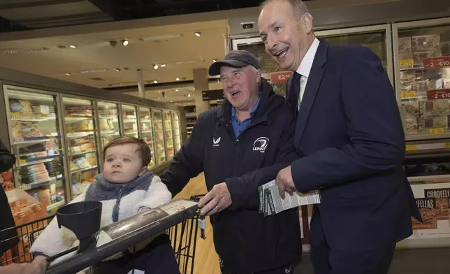 Tanaiste and Fianna Fail leader Micheal Martin, right, meets Barney Hynes and his grandson Wyatt McLoughlin in Arklow, Ireland, on the last day of campaigning on the eve of the General Election, Thursday Nov. 28, 2024. (Brian Lawless/PA via AP)