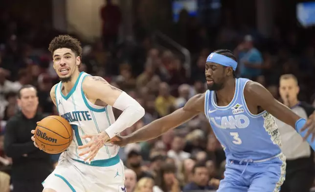 Charlotte Hornets' LaMelo Ball (1) drives past Cleveland Cavaliers' Caris LeVert (3) during the second half of an NBA basketball game in Cleveland, Sunday, Nov 17, 2024. (AP Photo/Phil Long)