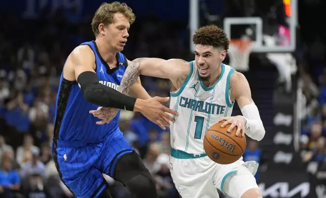 Charlotte Hornets guard LaMelo Ball (1) drives past Orlando Magic center Moritz Wagner, left, during the first half of an Emirates NBA Cup basketball game, Tuesday, Nov. 12, 2024, in Orlando, Fla. (AP Photo/John Raoux)