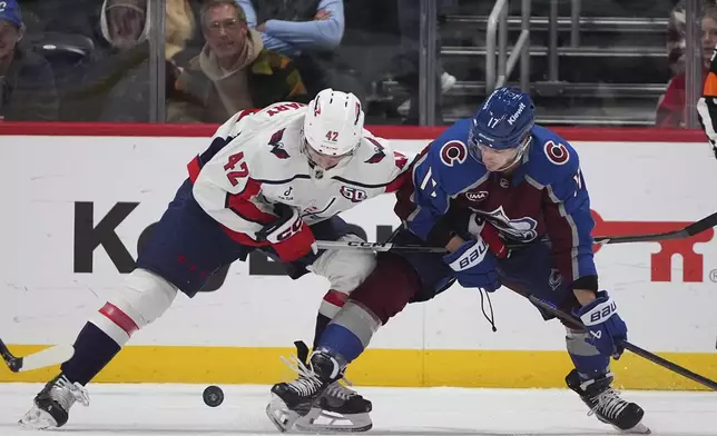 Washington Capitals defenseman Martin Fehervary, left, fights for control of the puck with Colorado Avalanche center Parker Kelly, right, in the second period of an NHL hockey game Friday, Nov. 15, 2024, in Denver. (AP Photo/David Zalubowski)