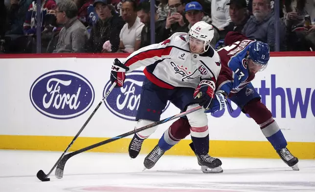 Washington Capitals center Connor McMichael, left, pursues the puck with Colorado Avalanche right wing Valeri Nichushkin, right, in the second period of an NHL hockey game Friday, Nov. 15, 2024, in Denver. (AP Photo/David Zalubowski)