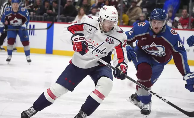 Washington Capitals center Connor McMichael, left, sweeps past Colorado Avalanche defenseman Josh Manson, right, to score in the second period of an NHL hockey game Friday, Nov. 15, 2024, in Denver. (AP Photo/David Zalubowski)