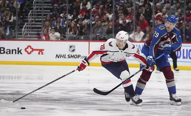 Washington Capitals center Lars Eller, left, loses control of the puck while driving past Colorado Avalanche center Nathan MacKinnon, right, in the second period of an NHL hockey game Friday, Nov. 15, 2024, in Denver. (AP Photo/David Zalubowski)