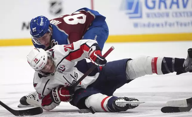 Washington Capitals center Nic Dowd (26) fights for control of the puck with Colorado Avalanche center Ivan Ivan (82) in the first period of an NHL hockey game Friday, Nov. 15, 2024, in Denver. (AP Photo/David Zalubowski)