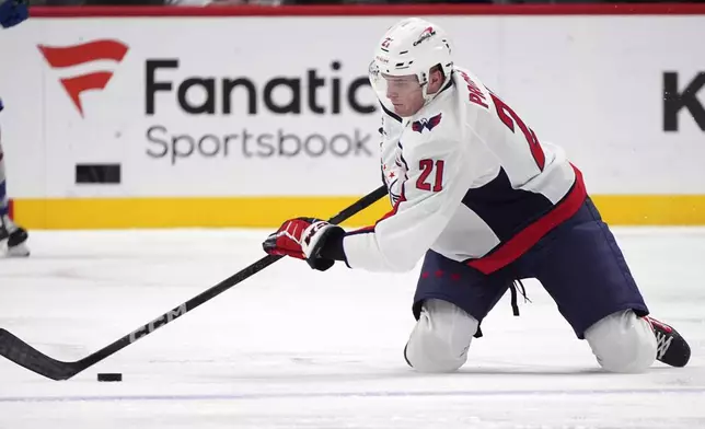 Washington Capitals center Aliaksei Protas struggles to collect the puck in the second period of an NHL hockey game against the Colorado Avalanche, Friday, Nov. 15, 2024, in Denver. (AP Photo/David Zalubowski)