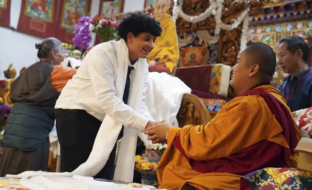 High school friends present U.S.-born Buddhist lama, Jalue Dorje, with a “khata,” the Tibetan ceremonial scarves that symbolize auspiciousness, at his 18th birthday and enthronement ceremony, in Isanti, Minn., on Saturday, Nov. 9, 2024. (AP Photo/Jessie Wardarski)