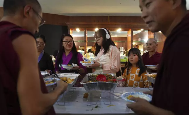 Guests and monks choose from a wide selection of homemade Tibetan dishes at the 18th birthday and enthronement ceremony for U.S.-born Buddhist lama, Jalue Dorje, in Isanti, Minn., on Saturday, Nov. 9, 2024. (AP Photo/Jessie Wardarski)