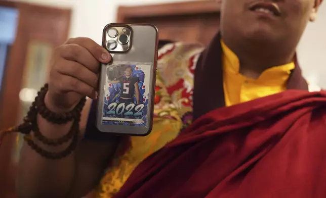 U.S.-born Buddhist lama, Jalue Dorje, shows his Drake London, Atlanta Falcons, rookie card, which sits in the back of his phone, at his 18th birthday and enthronement ceremony at the Tibetan American Foundation of Minnesota, on Saturday, Nov. 9, 2024, in Isanti, Minn. (AP Photo/Jessie Wardarski)