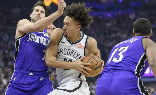 Brooklyn Nets forward Jalen Wilson, center, drives past Sacramento Kings forwards Doug McDermott, left, and Keegan Murray (13) during the first half of an NBA basketball game in Sacramento, Calif., Sunday, Nov. 24, 2024. (AP Photo/Randall Benton)