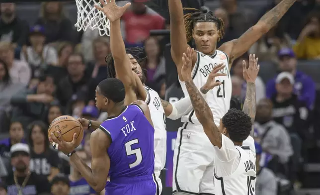 Sacramento Kings guard De'Aaron Fox (5) is guarded by Brooklyn Nets forward Trendon Watford, second from left, Noah Clowney (21) and Keon Johnson, right, during the first half of an NBA basketball game in Sacramento, Calif., Sunday, Nov. 24, 2024. (AP Photo/Randall Benton)