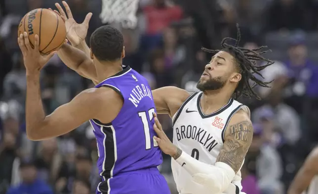 Sacramento Kings forward Keegan Murray, left, is guarded by Brooklyn Nets forward Trendon Watford, right, during the first half of an NBA basketball game in Sacramento, Calif., Sunday, Nov. 24, 2024. (AP Photo/Randall Benton)