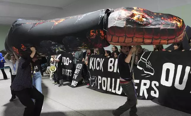 Kevin Buckland, right, and other activists participate in a demonstration against fossil fuels called weed out the snakes at the COP29 U.N. Climate Summit, Friday, Nov. 15, 2024, in Baku, Azerbaijan. (AP Photo/Joshua A. Bickel)