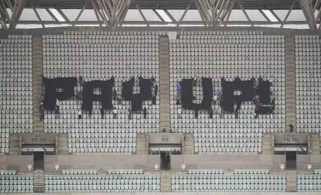 Activists with signs spell out "pay up" for climate finance in the Baku Olympic Stadium during the COP29 U.N. Climate Summit, Thursday, Nov. 14, 2024, in Baku, Azerbaijan. (AP Photo/Sergei Grits)