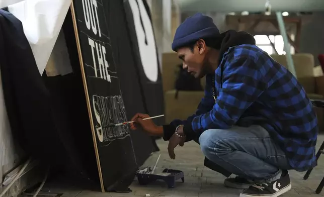 Shaq Koyok, of Malaysia, paints a sign ahead of a demonstration during the COP29 U.N. Climate Summit, Thursday, Nov. 14, 2024, in Baku, Azerbaijan. (AP Photo/Joshua A. Bickel)