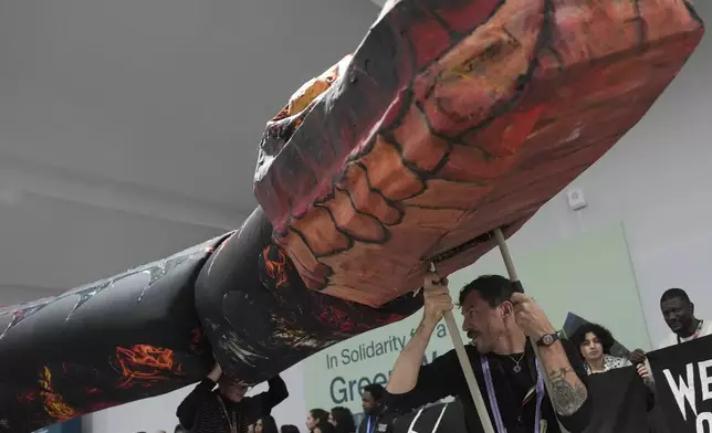 Kevin Buckland, front, and other activists participate in a demonstration against fossil fuels called weed out the snakes at the COP29 U.N. Climate Summit, Friday, Nov. 15, 2024, in Baku, Azerbaijan. (AP Photo/Joshua A. Bickel)