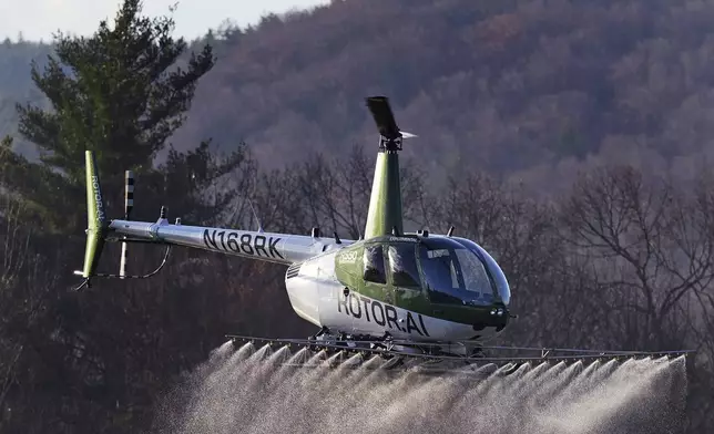 A Rotor Technologies unmanned semi-autonomous helicopter sprays a payload of water during a test flight over Intervale Airport, Monday, Nov. 11, 2024, in Henniker, N.H. (AP Photo/Charles Krupa)