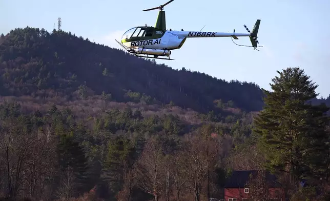 A Rotor Technologies unmanned semi-autonomous helicopter flies near Pat's Peak ski area, rear, during a test flight over Intervale Airport, Monday, Nov. 11, 2024, in Henniker, N.H. (AP Photo/Charles Krupa)