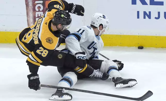 Boston Bruins defenseman Parker Wotherspoon (29) and Utah Hockey Club right wing Dylan Guenther (11) pursue the puck in the first period of an NHL hockey game, Thursday, Nov. 21, 2024, in Boston. (AP Photo/Steven Senne)