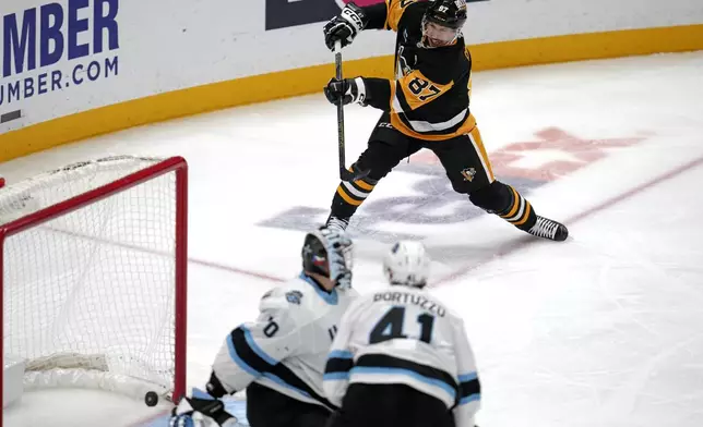 Pittsburgh Penguins' Sidney Crosby (87) gets a shot behind Utah Hockey Club goaltender Karel Vejmelka (70) for his 600th career goal in the NHL during the second period of an NHL hockey game Saturday, Nov. 23, 2024, in Pittsburgh. (AP Photo/Gene J. Puskar)