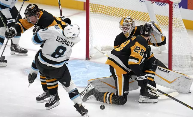 Utah Hockey Club's Nick Schmaltz (8) is checked off his skates by Pittsburgh Penguins' Sidney Crosby (87) after getting off a shot in front of Pittsburgh Penguins goaltender Alex Nedeljkovic (39) with Marcus Pettersson (28) defending during the second period of an NHL hockey game, Saturday, Nov. 23, 2024, in Pittsburgh. (AP Photo/Gene J. Puskar)