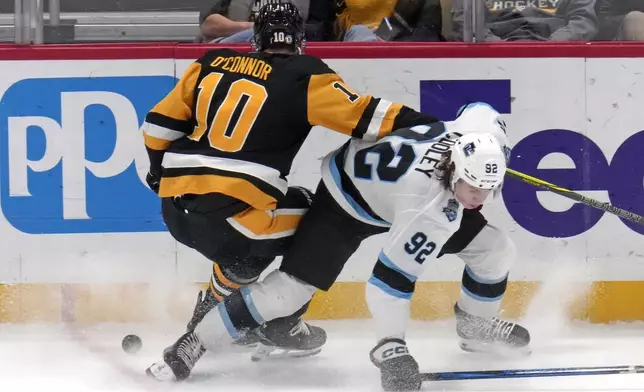 Pittsburgh Penguins' Drew O'Connor (10) loses control of the puck with Utah Hockey Club's Logan Cooley (92) defending during the first period of an NHL hockey game Saturday, Nov. 23, 2024, in Pittsburgh. (AP Photo/Gene J. Puskar)