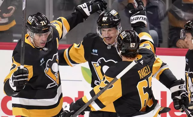 Pittsburgh Penguins' Sidney Crosby (87) celebrates after getting his 600th career goal in the NHL with Evgeni Malkin (71) and Rickard Rakell (67), during the second period of an NHL hockey game against the Utah Hockey Club, Saturday, Nov. 23, 2024, in Pittsburgh. (AP Photo/Gene J. Puskar)