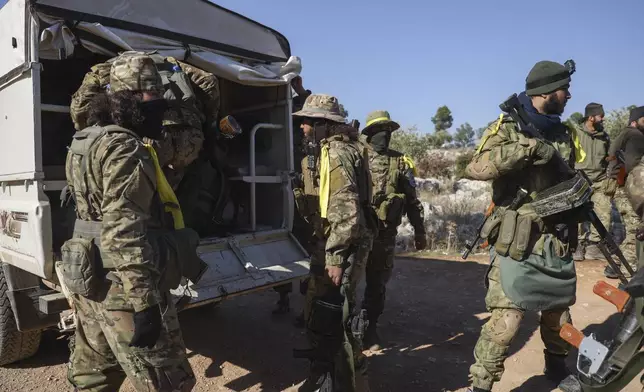 Syrian opposition fighters get off a truck as they enter the village of Anjara, western outskirts of Aleppo, Syria, Thursday Nov. 28, 2024, part of their major offensive on government-controlled areas in the country's northwestern Syria. (AP Photo/Omar Albam)