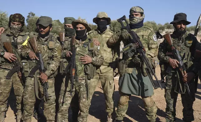 Syrian opposition fighters stand in formation after entering the village of Anjara, western outskirts of Aleppo, Syria, Thursday Nov. 28, 2024, part of their major offensive on government-controlled areas in the country's northwestern Syria. (AP Photo/Omar Albam)