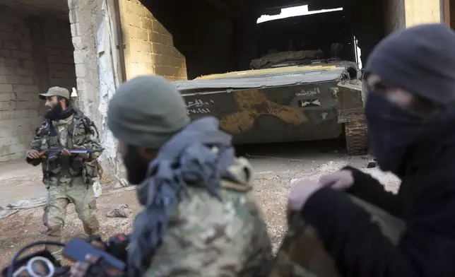 Syrian opposition fighters ride in front of a tank they allegedly captured from Syrian Government troops in Talhiya, Idlib countryside, Syria, Friday, Nov. 29, 2024. (AP Photo/Ghaith Alsayed)