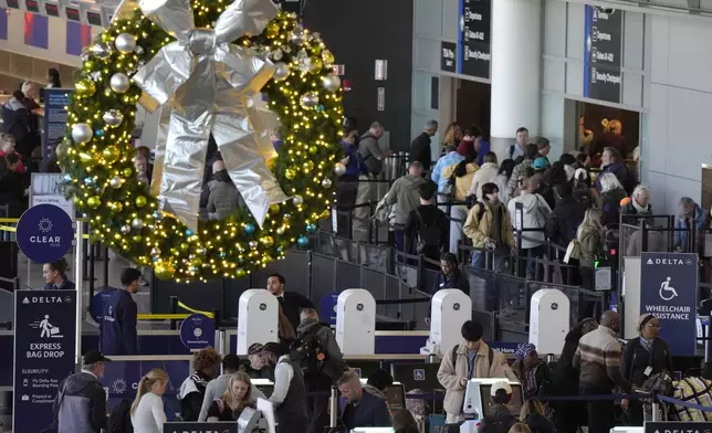 Travelers prepare to board aircraft near a holiday decoration, top, Monday, Nov. 25, 2024, at Boston Logan International Airport, in Boston. (AP Photo/Steven Senne)