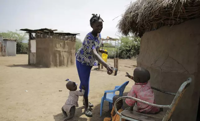 FILE - Winnie Keben gives water to her son at Meisori village in Baringo County, Kenya, July 20, 2022. Keben lost her leg to a crocodile attack, and that accident plus the loss of her home to rising water drove her and her family from their village. (AP Photo/Brian Inganga, File)