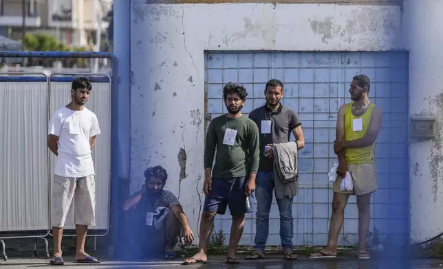 FILE - Survivors of a migrant shipwreck stand outside a warehouse at the port in Kalamata town, southwest of Athens, Greece, on June 15, 2023. (AP Photo/Thanassis Stavrakis, File)