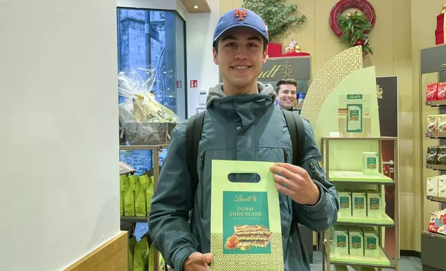 Student Esko Rieck poses with a bag containing a limited bar of 'Dubai Chocolate' after he bought it in the Lindt chocolate shop, in Aachen, Germany, Thursday, Nov. 14, 2024. (AP Photo/Daniel Niemann)