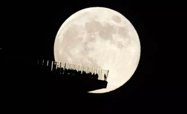 The moon rises behind an observation deck in New York City as seen from Hoboken, N.J., Friday, Nov. 15, 2024. (AP Photo/Seth Wenig)