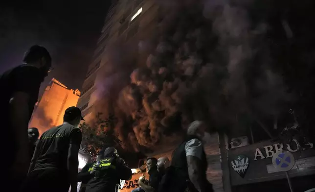 Firefighters and rescuers gather outside a computer shop hit in an Israeli airstrike in central Beirut, Sunday, Nov. 17, 2024. (AP Photo/Bilal Hussein)