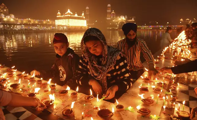 Sikh devotees light clay lamps next to the pond surrounding the Golden Temple as they celebrate the birth anniversary of the first Sikh guru, Guru Nanak, in Amritsar, India, Friday, Nov. 15, 2024. (AP Photo/Prabhjot Gill)