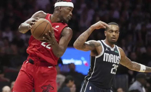 Miami Heat forward Jimmy Butler (22) grabs a rebound over Dallas Mavericks forward P.J. Washington (25) during the first half of an NBA basketball game, Sunday, Nov. 24, 2024, in Miami. (AP Photo/Jim Rassol)