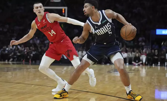 Dallas Mavericks guard Quentin Grimes (5) takes a step back to shoot as Miami Heat guard Tyler Herro (14) defends during the first half of an NBA basketball game, Sunday, Nov. 24, 2024, in Miami. (AP Photo/Jim Rassol)